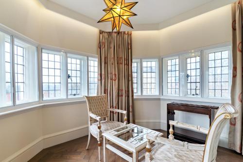 a room with a chair and a desk and windows at The LaLit London in London
