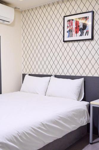 a bedroom with a white bed with a picture on the wall at Hyuzen Hotel - 휴젠 in Seoul