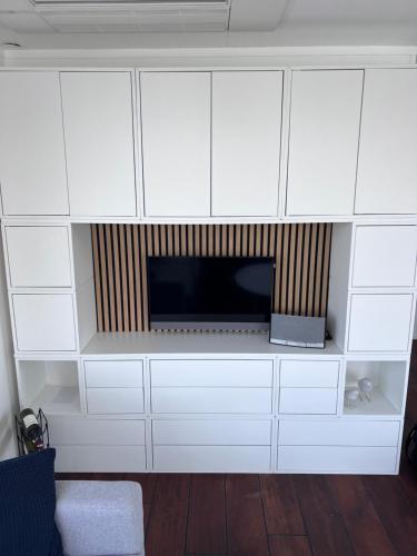 a living room with a tv and white cabinets at Oktopus-Lofts - Houseboat in Lelystad
