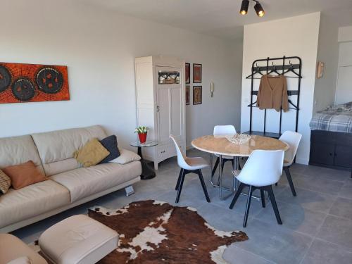 een woonkamer met een bank, een tafel en stoelen bij EnJOY Zee en uitzicht op Hinterland Westende in Middelkerke