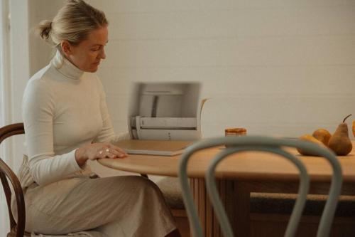 a woman sitting at a table with a computer at Herrings House, an iconic designer nature retreat in Willunga