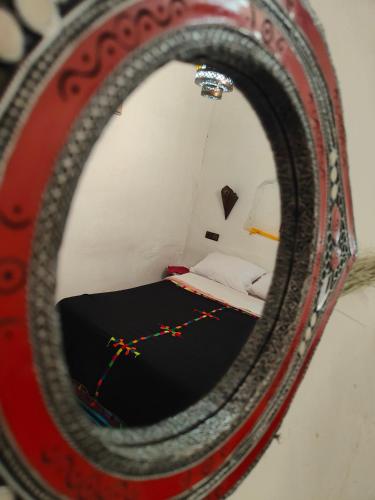 a mirror with a reflection of a bed in a room at Le Retour au calme Maison d'hôtes in Tinerhir