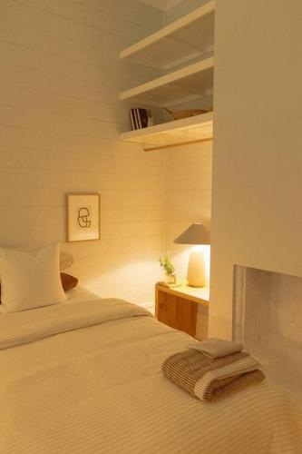 a bedroom with a bed and a table with a lamp at Herrings House, an iconic designer nature retreat in Willunga