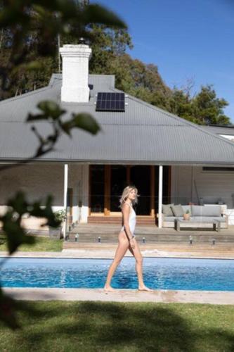 a woman walking next to a swimming pool at Herrings House, an iconic designer nature retreat in Willunga