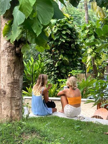two women sitting on the grass under a tree at 360 Surf Camp in Kuta Lombok