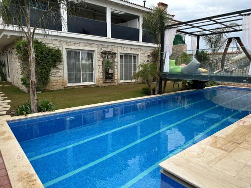 a large blue swimming pool in front of a house at Grand Alaçatı Butik Hotel in Alacati