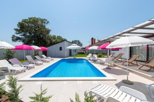 a swimming pool with lounge chairs and umbrellas at Nino with Shared Pool in Poreč