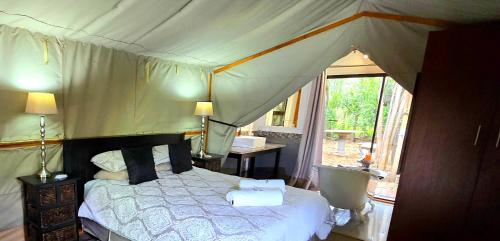 a bedroom with a bed in a tent at Old Mill Lodge, Seasonal Working Ostrich Farm & Restaurant, Oudtshoorn in Oudtshoorn