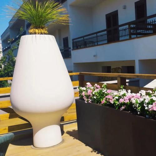a white vase with a plant in it next to flowers at Regina di Puglia in Santeramo in Colle