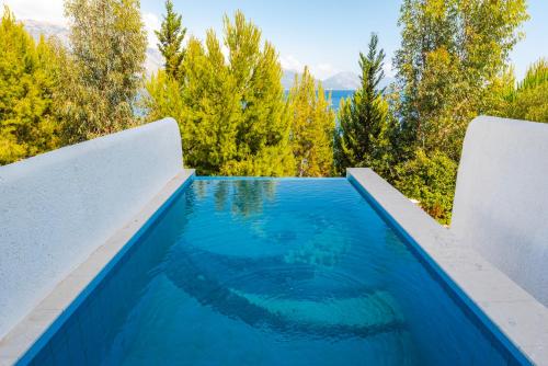 a swimming pool with trees in the background at Stone Beach Residence - Adults Only Resort in Qeparo