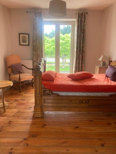 - une chambre avec un lit doté de draps rouges et une fenêtre dans l'établissement Maison place champs de foire 6 pers 3 chambres jardin terrasse, à Chamberet