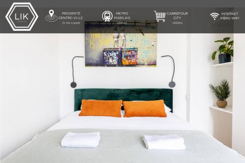 a bedroom with a white bed with orange pillows at LIK APPARTS MABILAY in Rennes