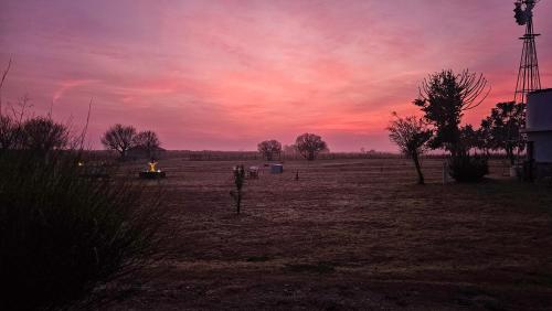 a sunset in a field with a windmill at Alma Drabble in José Enrique Rodó