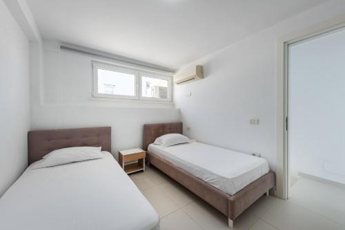 a bedroom with two beds and a window at Stone Beach Residence - Adults Only Resort in Qeparo