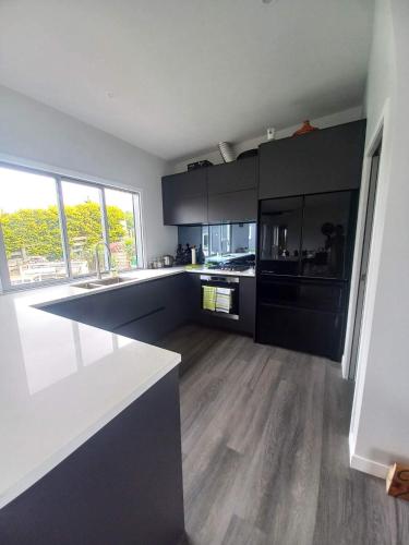 a large kitchen with black cabinets and wooden floors at Moko Hiwi Escape Ruakaka - Tūī Suite in Ruakaka