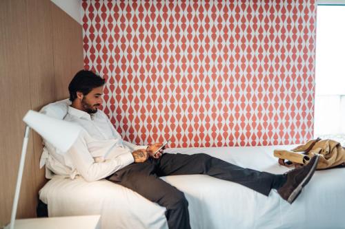 a man sitting on a bed looking at his watch at Stay Hotel Porto Centro Trindade in Porto
