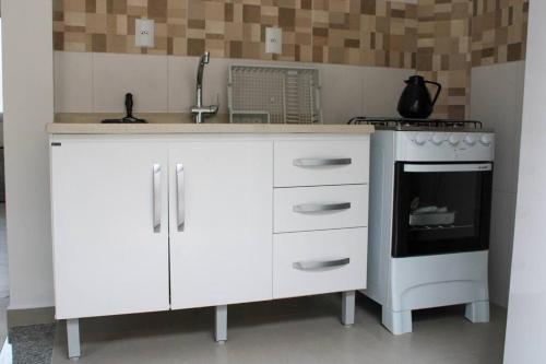 a white kitchen with a sink and a stove at Riviera de Garopaba Unidade Lumina - A Beira Mar in Garopaba