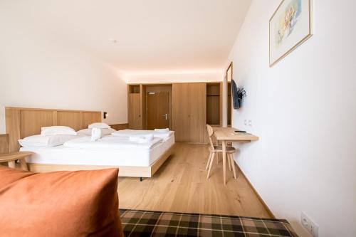 a bedroom with two beds and a desk at Hotel Taufers in Molini di Tures
