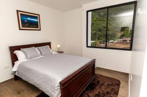 Un dormitorio con una cama y una ventana grande en MV Departamento 2, en Baños