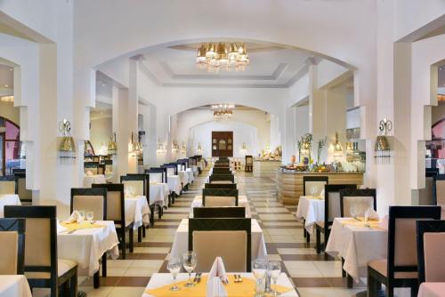 ein Esszimmer mit weißen Tischen und Stühlen in der Unterkunft Swisstouch Resort Marsa Alam in Bucht von Coraya