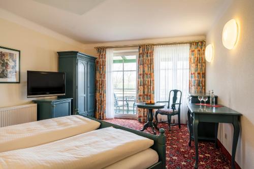 a hotel room with a bed and a desk and a television at Hotel am Haslinger Hof in Bad Füssing