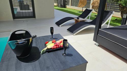 a table with a bowl of fruit and two wine glasses at Kooba Villas in Gázion