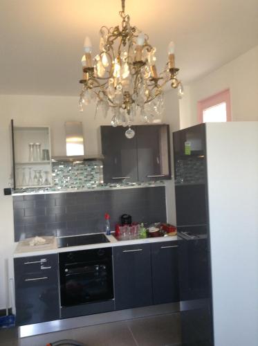 une cuisine avec des placards noirs et un lustre dans l'établissement T2 accueil proche Paris, à Sartrouville