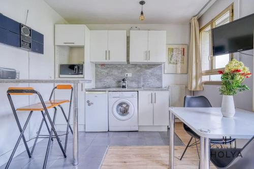 une cuisine avec des armoires blanches et une table avec des chaises dans l'établissement Le Fondamental - Proche Montparnasse - 252B, à Paris