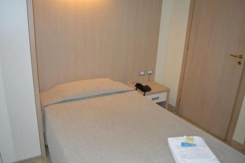 a small bedroom with a bed and a telephone at La Lanterna Hotel in Rometta Marea