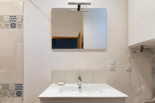 a white bathroom with a sink and a mirror at La Maison Tonio in Ossun