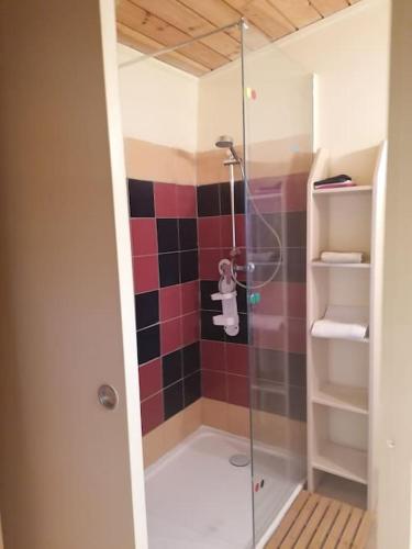 La salle de bains est pourvue d'une douche avec du carrelage rouge et noir. dans l'établissement le logis en bois, à Saint-Mathieu-de-Tréviers