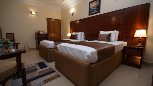 a hotel room with two beds and a couch at World Inn by WI Hotel in Karachi
