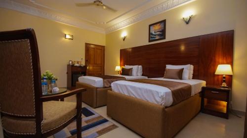 a hotel room with two beds and a chair at World Inn by WI Hotel in Karachi