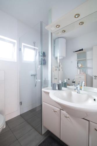 a white bathroom with a sink and a shower at Rosie in Valbandon