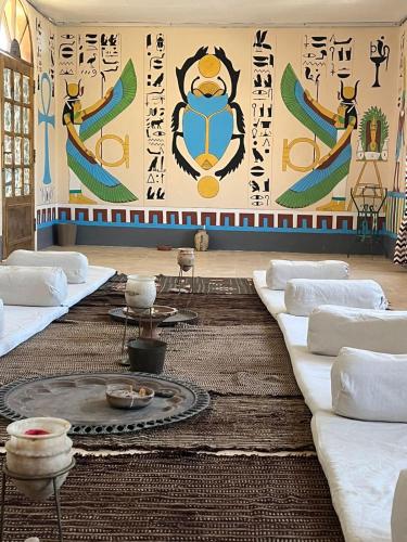 a living room with couches and a wall with a mural at Janat Elsahara Hotel in Luxor