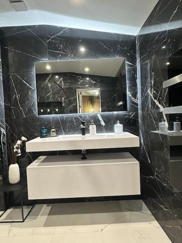 une salle de bain avec un lavabo blanc et un miroir dans l'établissement Villa plain pied avec piscine, à Saint-Paul-en-Forêt