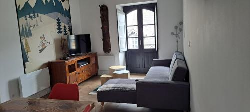 un salon avec un canapé et une télévision dans l'établissement Location T3 Centre ville avec parking, à Esquièze - Sère
