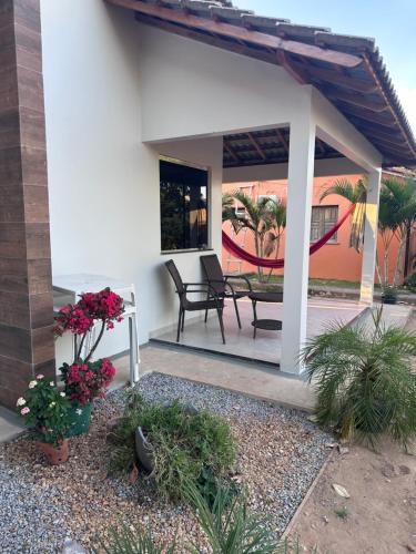 a house with a patio with two chairs and flowers at Fazenda Buritizal Grosso in Bonfim