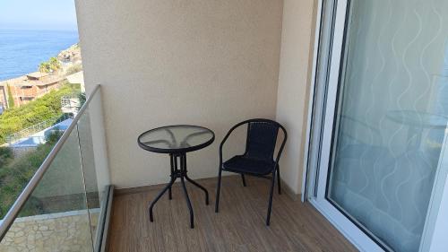a table and chair on a balcony with a view of the ocean at Your Home Montenegro in Dobra Voda