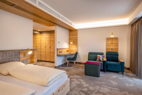 a bedroom with a bed and a desk and chairs at Hotel FrechDachs in Bad Füssing