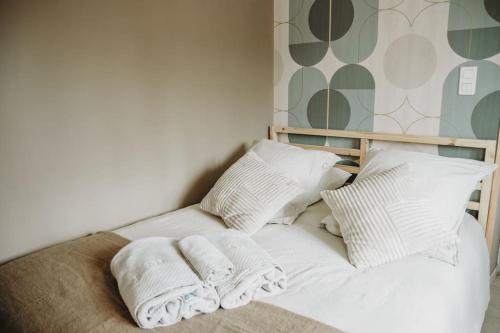 un lit avec des oreillers blancs et des serviettes dessus dans l'établissement Petite maison cosy Chez Georges, à Auxonne