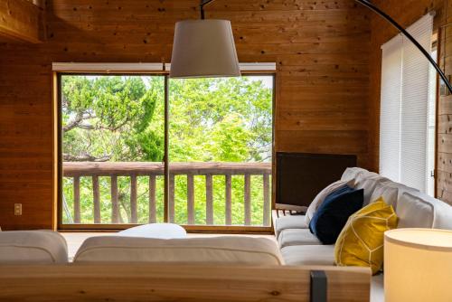a living room with a couch and a large window at Cottage Coliberty in Nakashima