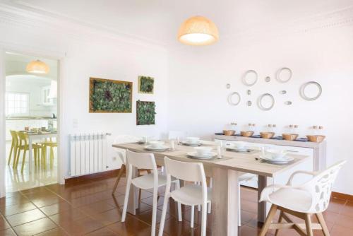 a dining room with a table and white chairs at Lavanda Village Cascais - Villa Flamingo in Cascais