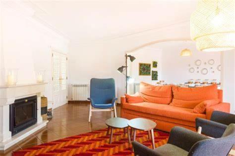 a living room with an orange couch and a blue chair at Lavanda Village Cascais - Villa Flamingo in Cascais
