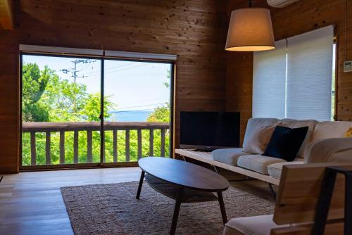 a living room with a couch and a table and a large window at Cottage Coliberty in Nakashima