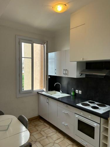 une cuisine avec des armoires blanches, un évier et une fenêtre dans l'établissement La finestra sul mare, à Antibes
