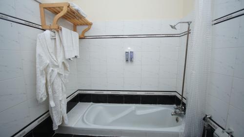 a white bath tub in a bathroom with white tiles at World Inn by WI Hotel in Karachi