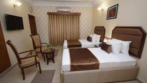 a hotel room with two beds and a chair and a table at World Inn by WI Hotel in Karachi