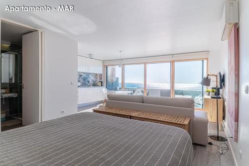 a bedroom with a bed and a couch and windows at Season Apartments in Sesimbra