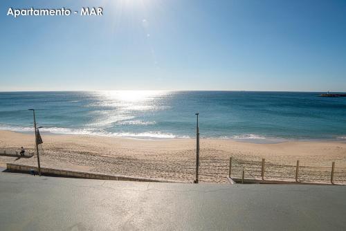 a beach with a fence and the ocean at Season Apartments in Sesimbra